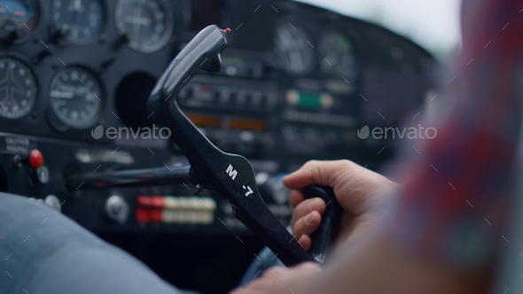 Aviator turning steering wheel private airplane cockpit on aerodrome close up.