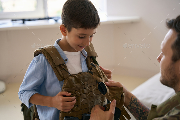 Military man showing army gloves to excited kid