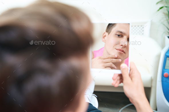 Young man estimating results after cosmetological procedures - Stock Photo - Images