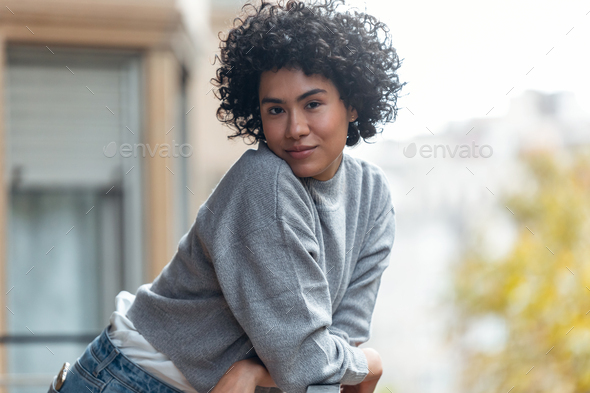 Beautiful woman posing while looking at camera standing in the balcony at home. - Stock Photo - Images