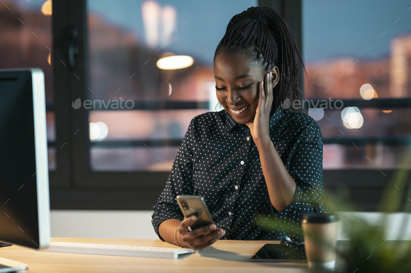 Beautiful business woman sending messages with mobile phone while working in the office. - Stock Photo - Images
