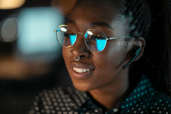 Smart business woman working with computer while talking with earphone sitting on desktop - Stock Photo - Images