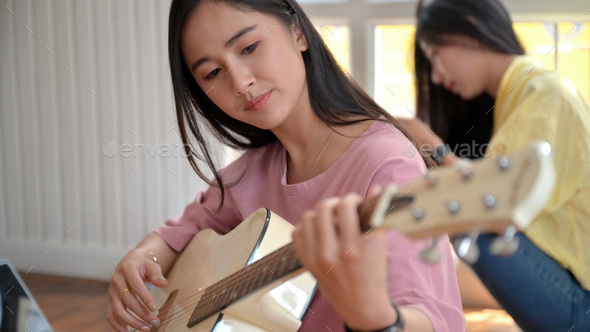 Teenage girl playing guitar with friends.