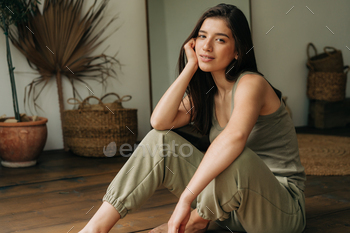 Portrait of a serene beautiful young brunette woman sitting on the floor.