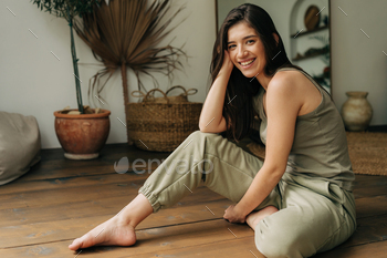 Portrait of a happy cheerful beautiful young brunette woman sitting on the floor.