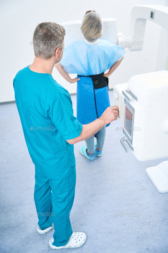 Doctor performing knee xray procedure on caucasian female patient