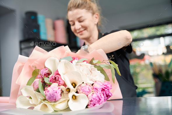Portrait of happy woman florist with bouquet in flower boutique