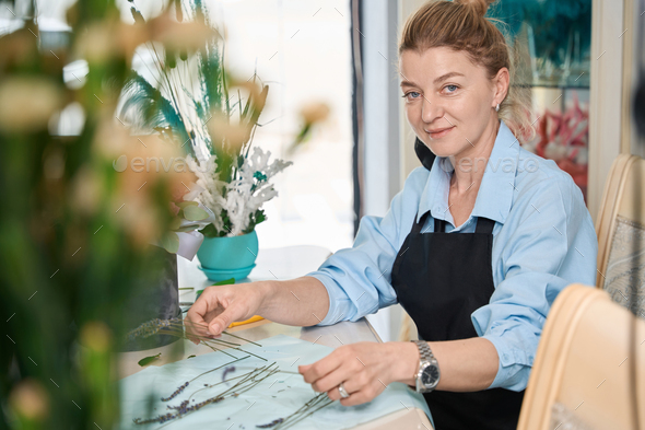 Smiling florist with lavender in hand, conducts online lesson