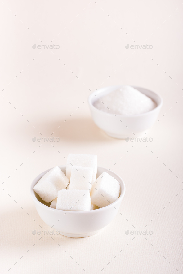 Sugar cubes and granulated sugar in bowls. Choosing between types of