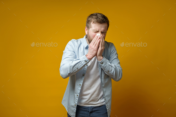 Man is sick, has a runny nose, he coughs or sneezes, covering mouth with a handkerchief