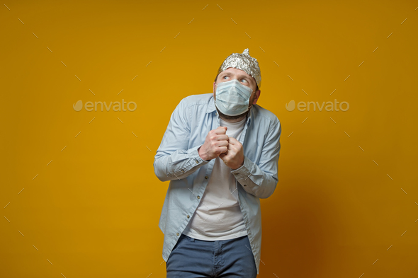 Oddball man in a medical mask is very afraid of contracting the virus, he put on a tin foil hat