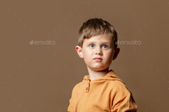 Little kid boy in brown hoodie on brown background