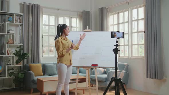 Asian Female Teacher Shoots Video By Smartphone Camera While Teaching English At Home alt