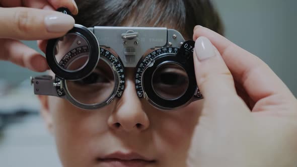 Ophthalmologist Examining Little Boy Inserting a Lens Into Lens Testing Eye Glasses Frame alt