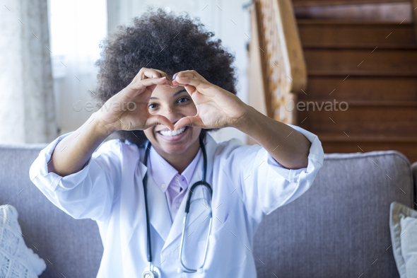 Woman physician doing heart shape gesture with hands. Smiling black female doctor making a love symb