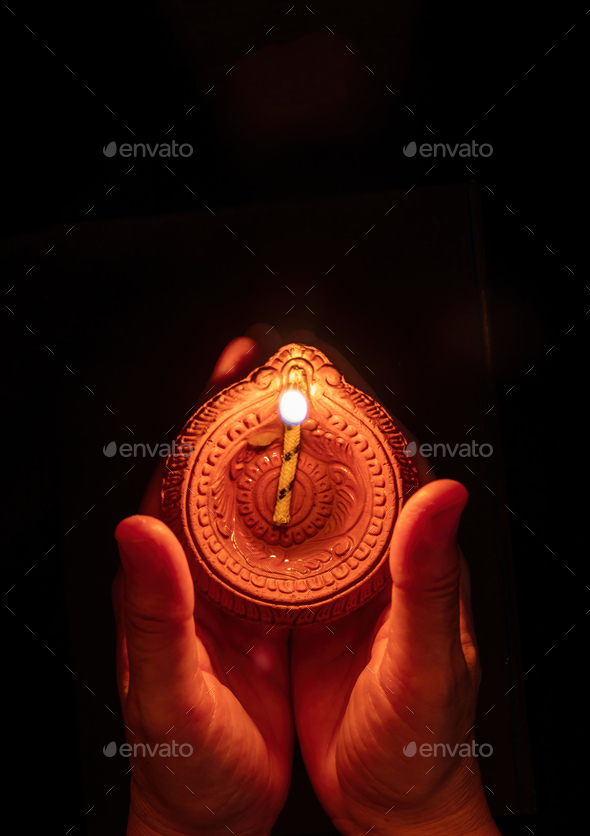 Diwali Festival of lights celebration. Diya lamp in woman hands, top view