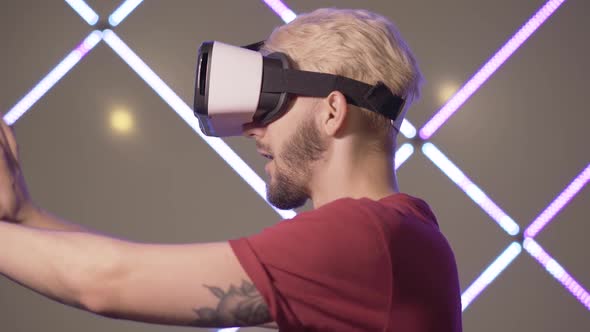 Side View of Excited Young Man in VR-glasses Touching Invisible Wall. Close-up of Cheerful Smiling alt