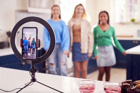 Group Of Teenage Girls In Bedroom Recording Online Dance Video On Mobile Phone For Social Media