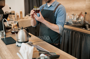barista holds a glass of fragrant filter coffee in his hands
