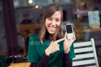 Portrait of cheerful young caucasian woman in green clothes that sitting outside cafe