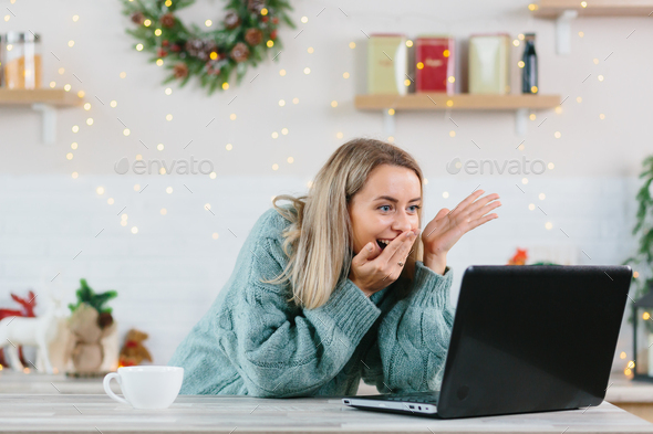 A woman shocked with happiness rejoiced looking at a laptop monitor at home during the New Year and - Stock Photo - Images
