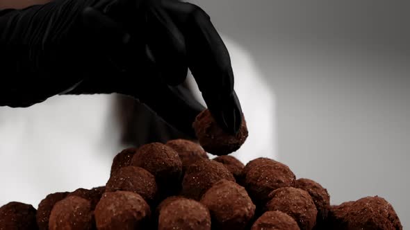 Chefs Hand in Black Glove Puts Truffle Candy on Top of Sweets Pile Slow Mo