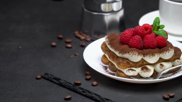 Portion of Tiramisu Dessert with Raspberries, Espresso and Coffee Maker on Concrete Background alt