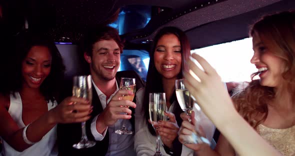 Happy friends drinking champagne in limousine alt