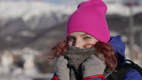 Closeup Portrait of a Woman in a Pink Hat and Blue Jacket Standing and Smiling on a City Winter alt