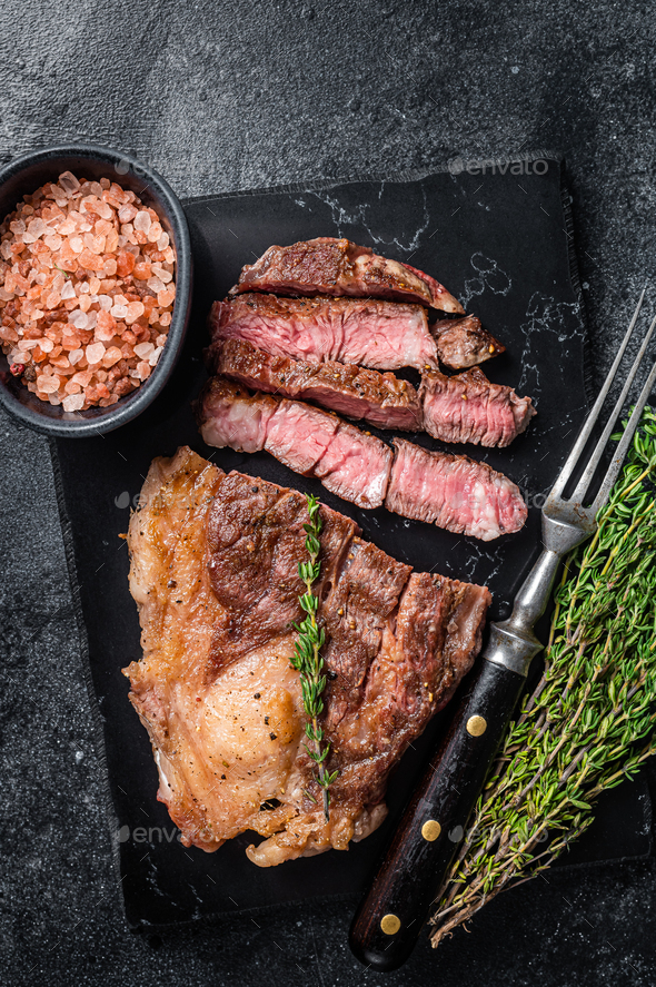 Roasted bbq Chuck Roll beef steaks with herbs. Black background. Top