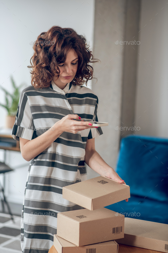 Focused woman scanning the QR code on the package - Stock Photo - Images