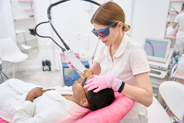 Esthetician carrying out hair removal procedure on beauty salon customer