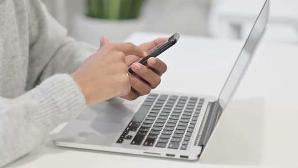Close Up of Hands of African Woman with Laptop Using Smartphone alt
