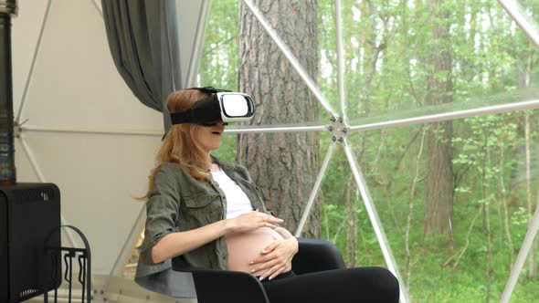 pregnant woman in virtual reality glasses plays with her stomach while alt