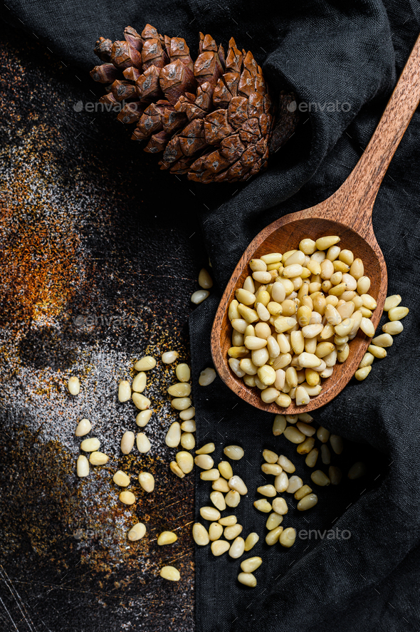 Pine nuts in the spoon and pine nut cone. Organic food. Black