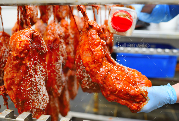 an employee of a butcher's shop or meat-packing plant sprinkles appetizing pieces of pork in tomato
