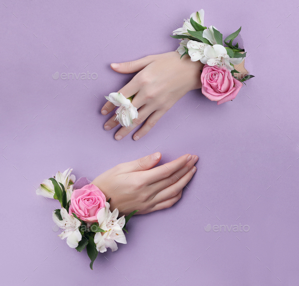 Beauty Hand with flowers in a hole in a purple paper background. Nature
