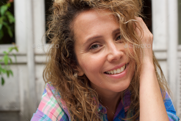 Close up happy woman with hand in curly hair - Stock Photo - Images