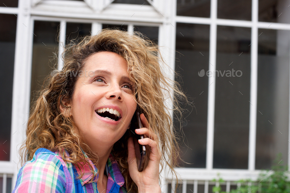 Close up happy woman talking with cellphone outside and looking away - Stock Photo - Images