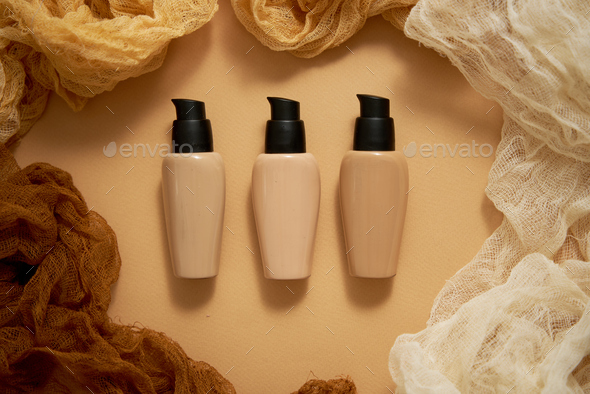 Bottles of three different shades of makeup foundation on beige