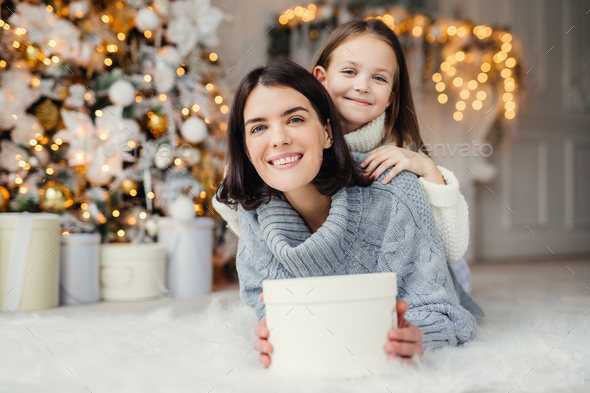 Indoor shot of mother and daughter have fun together, share presents ...