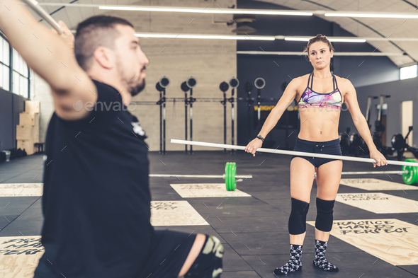 Woman trainer coaching body builder man weight lifting training