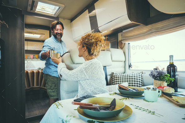 Couple living off grid inside a modern luxury camper van and enjoy travel lifestyle. People