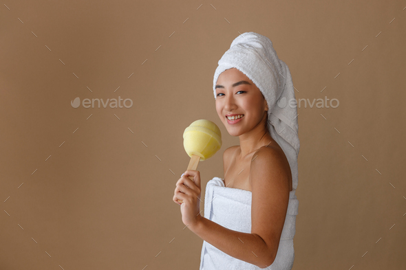 Joyful Asian woman holding lollipop bath sponge