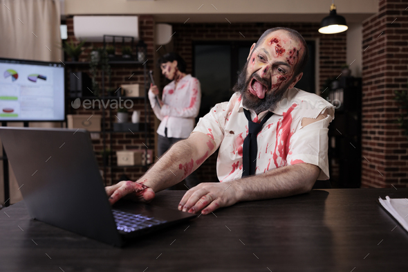 Creepy scary zombie using laptop at desk