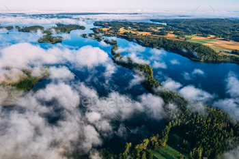 Aerial top view of mist cloud fog morning over blue lakes and green forests in Finland.