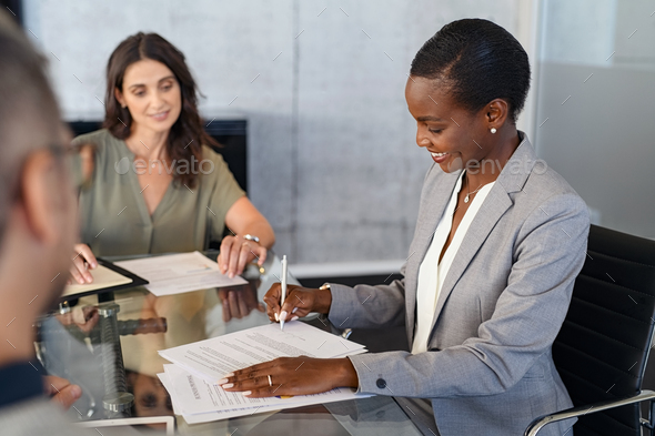 African businesswoman signing document during meeting - Stock Photo - Images