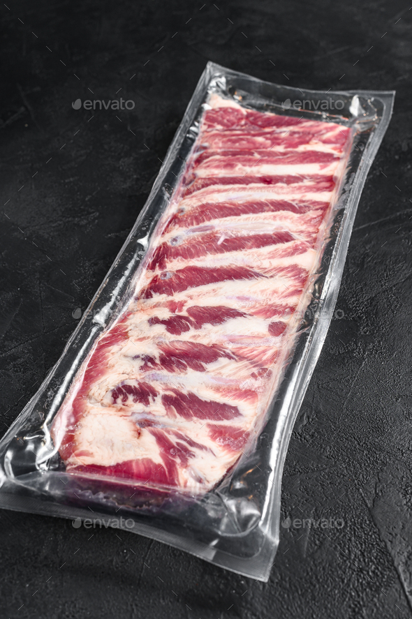 Raw pork ribs vacuum packed. Black background. Top view Stock Photo by