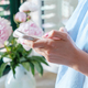 Young woman uses the phone on the background of beautiful pink peonies - PhotoDune Item for Sale