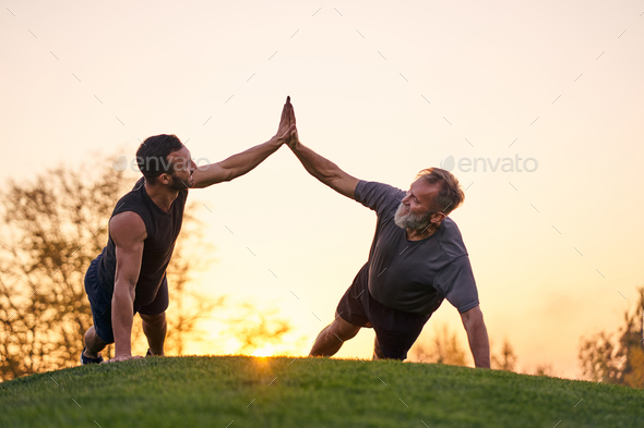 The two sportsmen push up together on the sunset background.